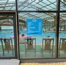 A glass door with a sign in the middle of a pool Description automatically generated