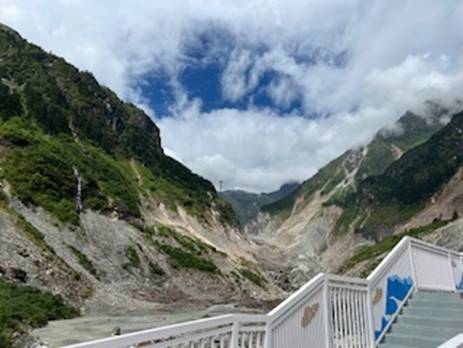 A white railing leading to a rocky mountain Description automatically generated